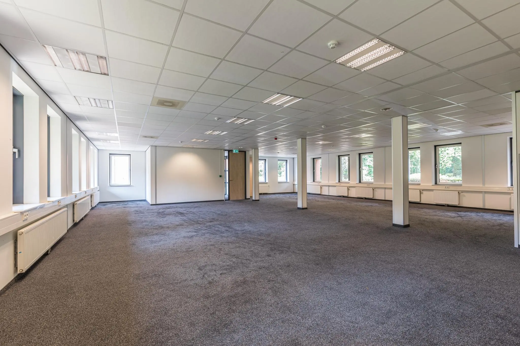 Ruime, lege kantoorruimte aan de Laan Blussé van Oud-Alblas met tapijtvloer, systeemplafond en meerdere ramen.